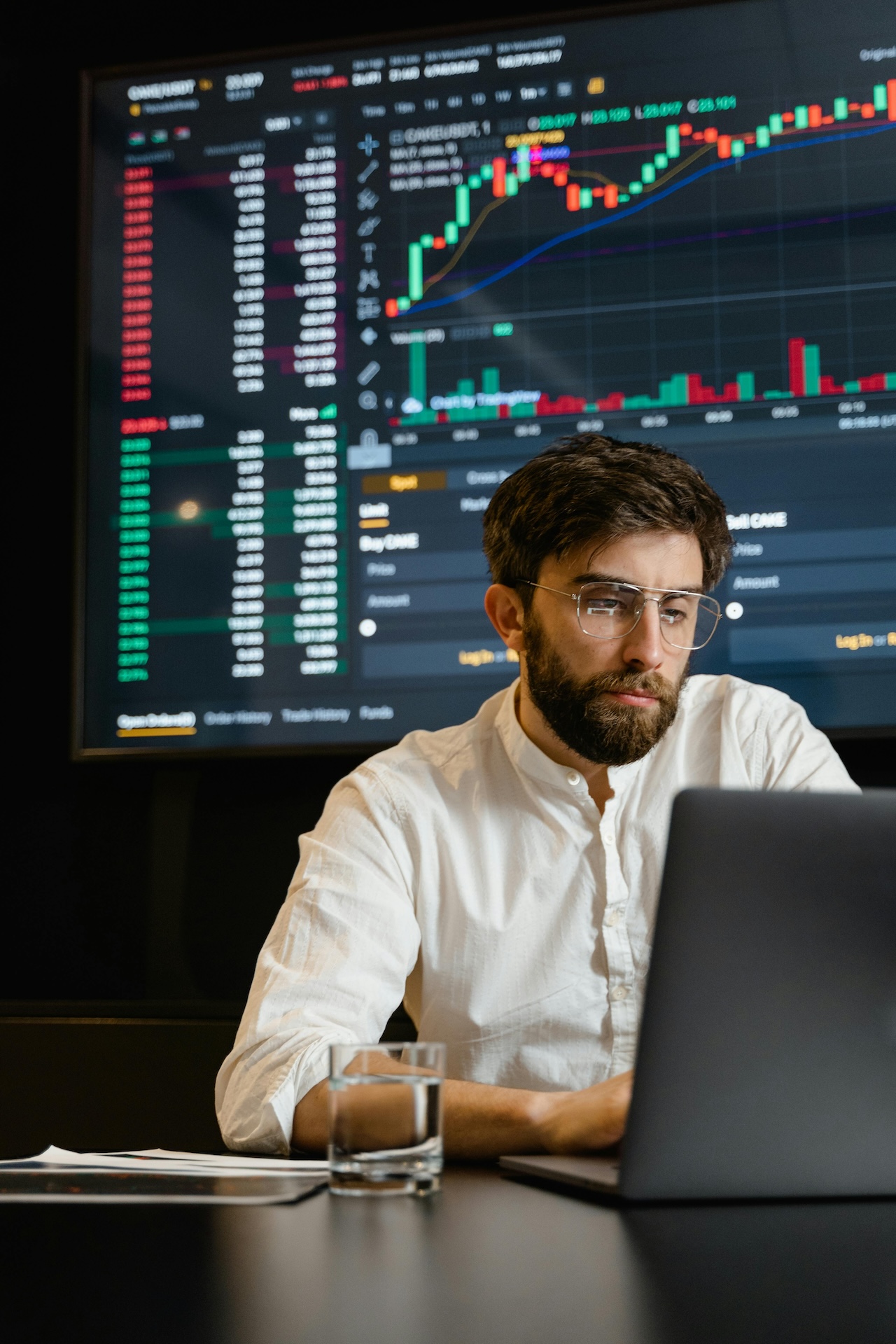 Männer vor Laptop mit Börsenkurve im Hintergrund